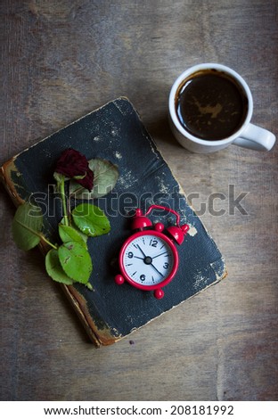 Cup of coffee, old book and dry red rose on the table