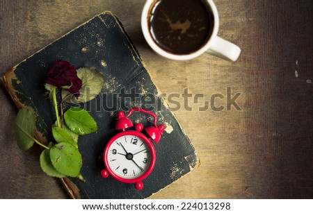 Cup of coffee, old book and dry red rose on the table