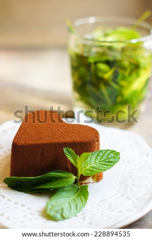 Tiramisu cake heart shaped with fresh mint, tea, red roses and note on the wodden background