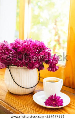 Autumn time, flowers in the vase and cup of coffee on the table with note
