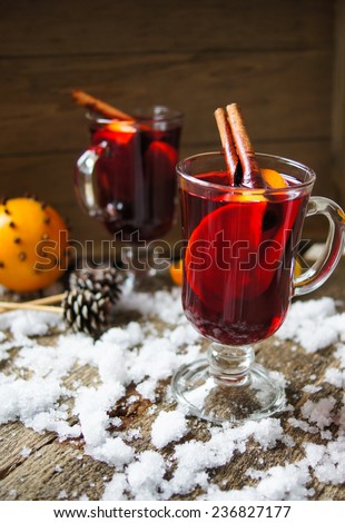 Glass with hot spiced wine with orange fruit, scarf and snow