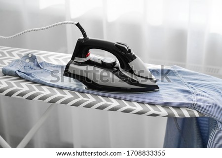 woman ironing men's blue shirt on an ironing board. Macro