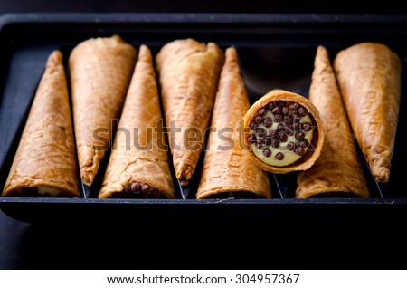 Wafer rolls filled with butter cream and chocolate crisps. Selective focus
