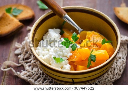 Grilled pumpkin with homemade cheese and herbs on wooden background