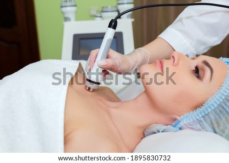 The spa salon's cosmetologist performs a RF lifting procedure on the neckline of a young woman. Stok fotoğraf © 