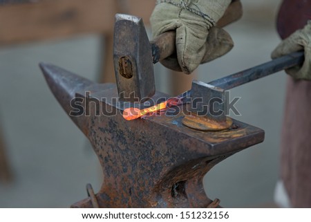 blacksmith working metal the oldfashioned way, with hammer and anvil and open fire