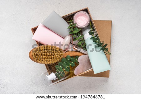 Beauty box with face and body care products on grey background. Tubes with cream and lotion, hydrophilic oil, facial roller, guache massager, body brush. Natural cosmetics gift Foto stock © 