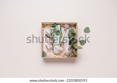 Beauty box with face and body care products on light background. Tubes with cream and lotion, facial roller, guache massager, eucalyptus leaves. Organic cosmetics gift Foto stock © 