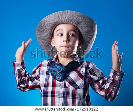 Studio shot of boy dressed up like kowboy pretends  he is surrendering.