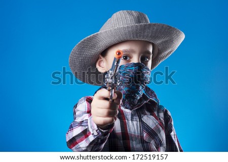 Studio shot of masked little cowboy with revolver toy.