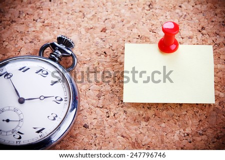 Blank note for your text hanged on the cork-board with an old pocket watch.