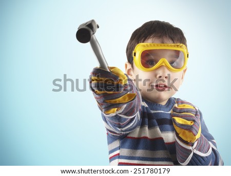 Studio shot of five years old child with worker gloves and hammer.