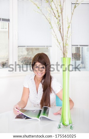 pretty smiling girl reads magazine at home
