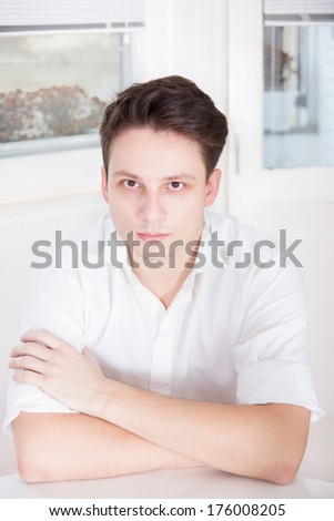 sick man in white shirt sitting with bags under eyes
