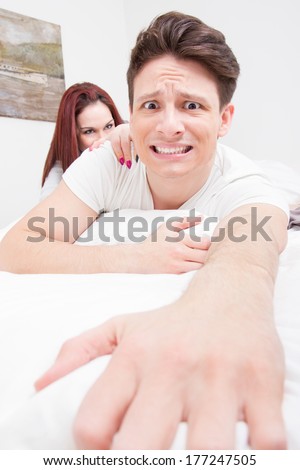 frightened and scared man trying to escape from the bed because he is afraid of woman