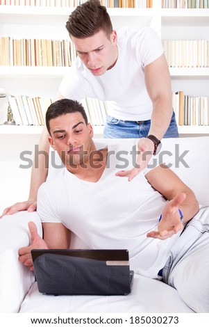 two surprised young people looking at laptop, over the internet