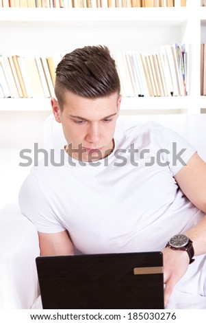 thoughtful young man chatting on laptop computer at home