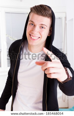 cool young guy with great smile in active sportswear hood pointing with finger at camera