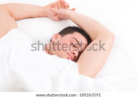 young man lying in bed and having sweet dreams while sleeping