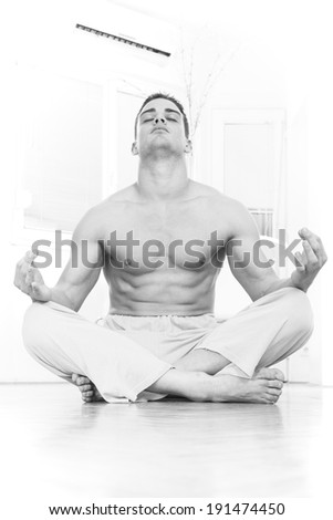young handsome muscular  half naked man doing yoga and meditating indoors, black and white effect style