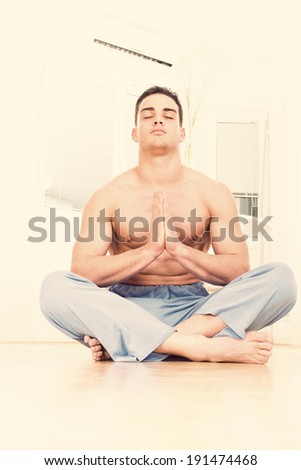 Caucasian half naked male in pajamas doing yoga prayer pose indoors in his apartment