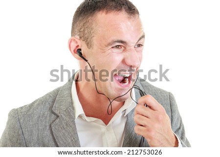 Angry man with earbuds connected on mobile phone yelling while talking over phone microphone