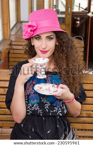 retro photo of cute girl in a wagon train sitting and drinking coffee or tea while looking in front of camera, vintage photo