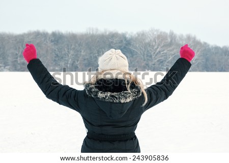winter happy woman in snow holding snow ball in hand for snowballing with thumb up outside on sunny cold winter vintage day.Portrait of smiling female model with pink gloves and hat with scarf in snow