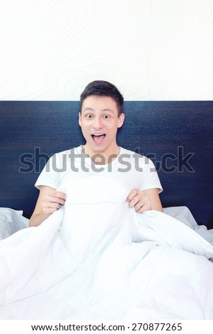 Man satisfied with his sex life showing happy reaction looking at his peny under sheets smiling