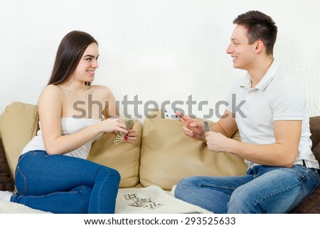 Couple playing cards enjoying game. Young adult couple relaxing playing blackjack. Boyfriend and girlfriend sitting on couch playing poker smiling
