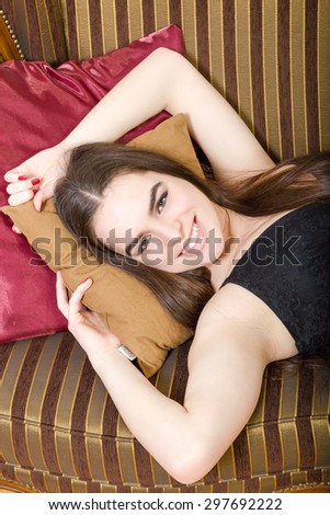 Elegant woman on magnificent sofa close up. Vogue style vintage portrait. Retro-stylized female in black dress sitting on retro couch smiling. Pretty girl in luxury interior lying.Lovely seduces photo