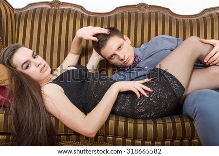 Retro vintage couple lying on the retro furniture. Young man and woman In sexy edition looking seductively at camera or at you. Vintage male and female model on sofa at home.