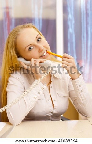 Woman talking by phone with pen in her hand.
