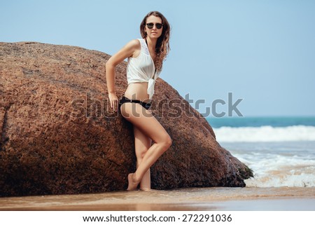 Portrait of sexy young Caucasian woman sitting on rocky coast with