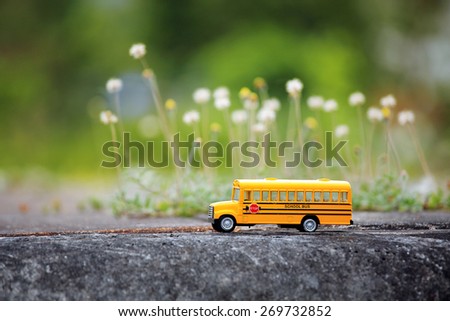 Yellow school bus toy model on country road.