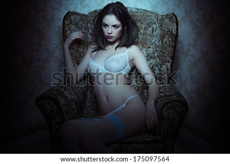 Beautiful provocative woman in lingerie sitting in an antique armchair with a highlight to her upper body