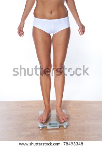Lower section legs of a young woman measuring her weight while standing on weighing machine