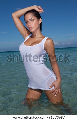 Curvaceous Woman In Slinky Wet Clothes, standing knee deep in the ocean and striking a provocative pose