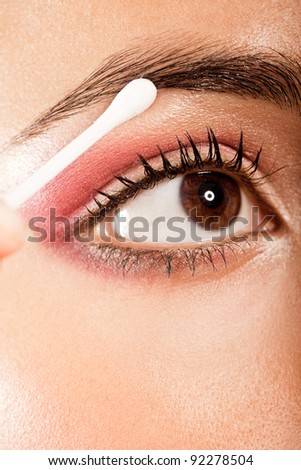 Applying Eye Makeup Eye Open. Woman with brown eyes using a cotton bud to blend her eye makeup, closeup on eye.