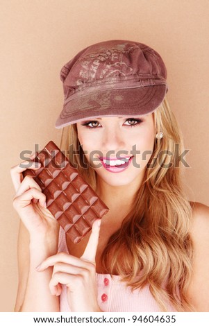 Laughing beautiful woman holding a slab of unwrapped chocolate close to her face.