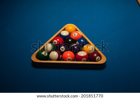 Colorful numbered pool object balls in a wooden triangular rack ready to start a new game or frame on blue baize