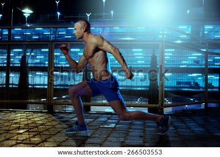 Handsome Young Athletic Guy with No Shirt Exercising Inside a Building Wile Facing to the Left of the Frame.