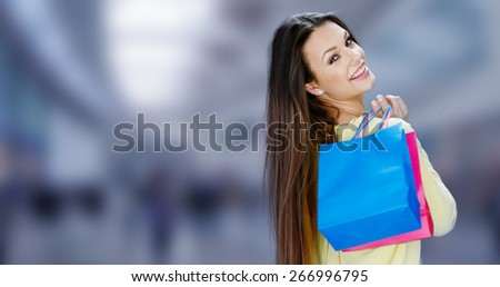 Happy attractive female shopper carrying her purchases in brightly colored carrier bags turning to smile over her shoulder at the camera