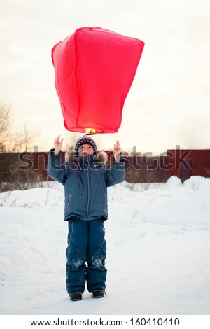 Happy boy flying fire lantern in the winter
