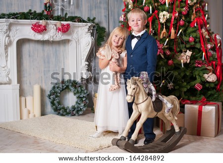 Happy brother and sister are embracing near Christmas tree. little friends enjoying New Year party, Christmastime holidays, best friends, happiness concept