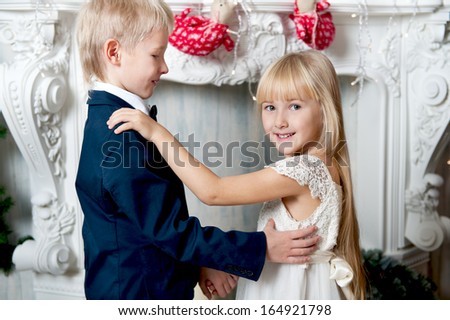Happy brother and sister dancing near fireplace. little friends enjoying New Year party, Christmastime holidays, best friends, happiness concept