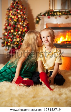 Happy brother and sister are playing on the floor near Christmas tree and fireplace. little friends enjoying New Year party, Christmastime holidays, best friends, happiness concept