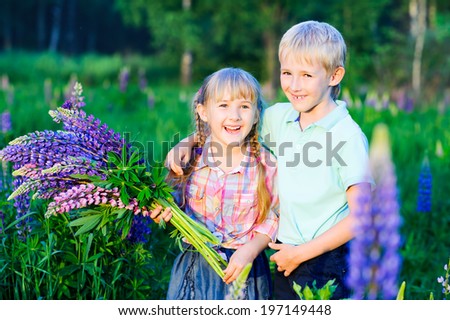 brother and sister hugging and laughing on the wildflowers field in summer