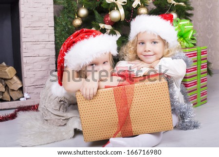 two  little girls in Santa\'s hat with Christmas gifts