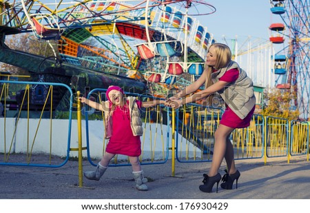 funny little girl with mom having fun in amusement park